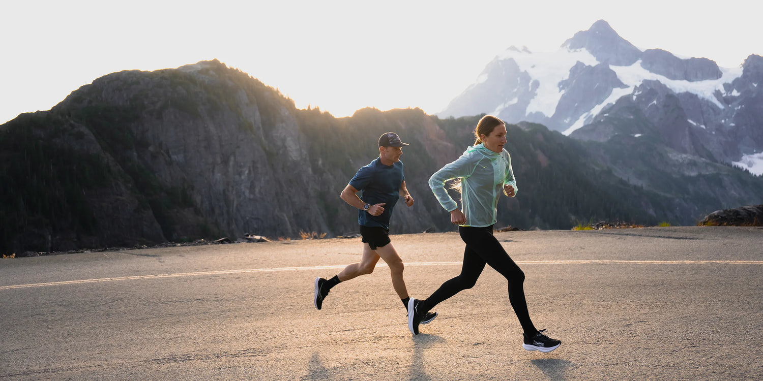 Man and Woman running up hill on road in the mountains wearing Superfeet active insoles.