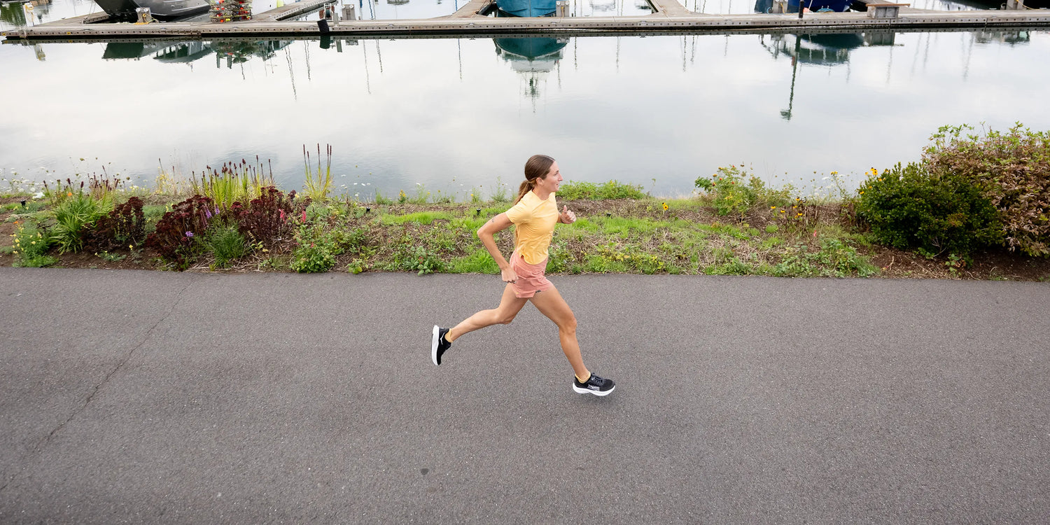 Woman running on sidewalk by a lake wearing Superfeet active support insoles.